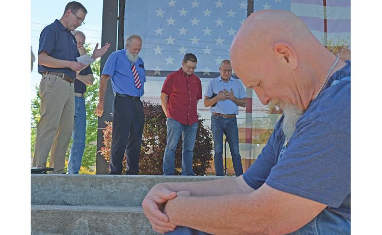 Ron Thompson bows his head as Dr. Phil Weaver (left) offers the prayer of repentance during White County’s National Day of Prayer ceremony. Pastors Joe Gist, Frank Zimmerman, Jeff Groves and Patrick Ballington also join in prayer behind Weaver on stage. (Photo/Samantha Sinclair)