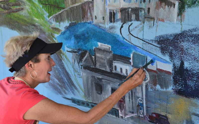 Anna Wilkins works on painting a new mural in Helen. (Photo/Stephanie Hill)