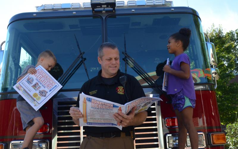 Beckham Vandegriff and Zurie Michele, kindergarteners at Mount Yonah Elementary School, were excited to look through the Hometown Heroes coloring book with Helen Fire Chief Jody Prickett. (Photo/Stephanie Hill)