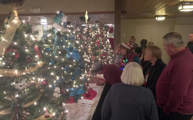 Guests had the opportunity to make last-minute bids on Christmas trees, sponsored by community businesses and organizations. (Photo/Wayne Hardy)