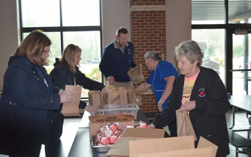 From left, White County School Superintendent Dr. Laurie Burkett, Director of School Improvement Cindy Free, White County Middle School Assistant Principal Lloyd Collins, WCMS school nutrition manager Linda Parker, and Rita Payne with school nutrition packed meals for the first day of pick-up at White County Middle School on March 16. (Photo/Stephanie Hill)