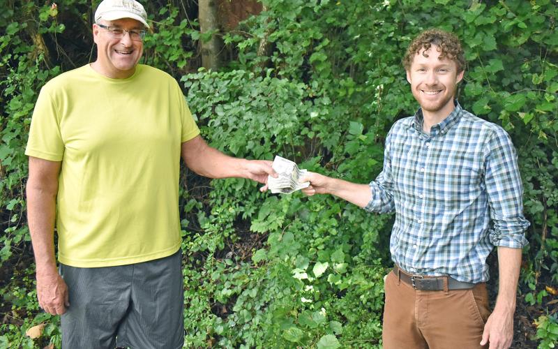 Matt Aiken, The Dahlonega Nugget publisher, hands Patrick Olmsted of Dahlonega, his prize money for winning The Mountain Traveler cover contest. (Submitted photo