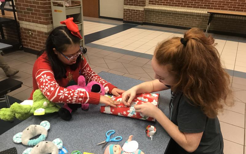 Brooke Puffer and Layla Herbert with Project Unify work together to wrap a present. (Submitted photo)