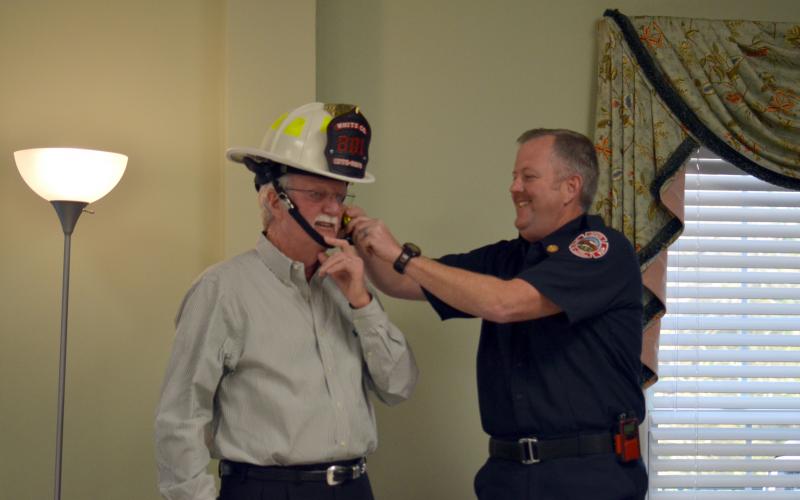 White County Fire Chief Seth Weaver assists Sheriff Neal Walden with securing a fire helmet presented as a gift.