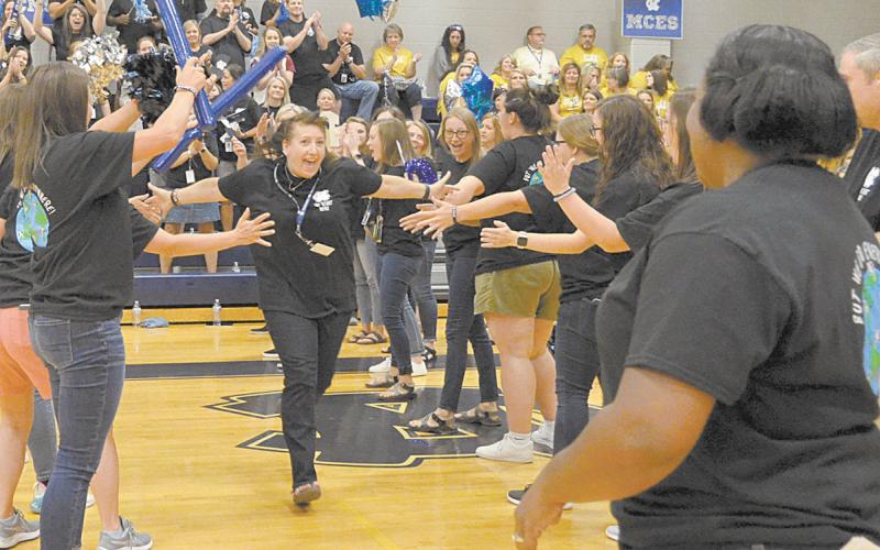 White County Middle School’s Dawn Powell runs through a lineup of fellow teachers on her way to celebrate with WCMS Principal Nara Allen during festivities a the school system’s back to school pep rally Aug. 2. (Photo/Wayne Hardy)