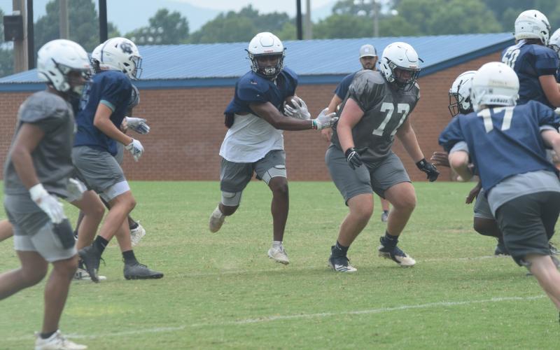 Zion McMullen, left, finds some running room off a block from Cameron Godfrey during Tuesday's practice session. The Warriors scrimmage East Forsyth next Friday night. (Photo/Mark Turner)