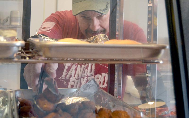Cajun Specialties co-owner David Spikes grabs some Cajun bites from a deli shelf. (Photo/Wayne Hardy)
