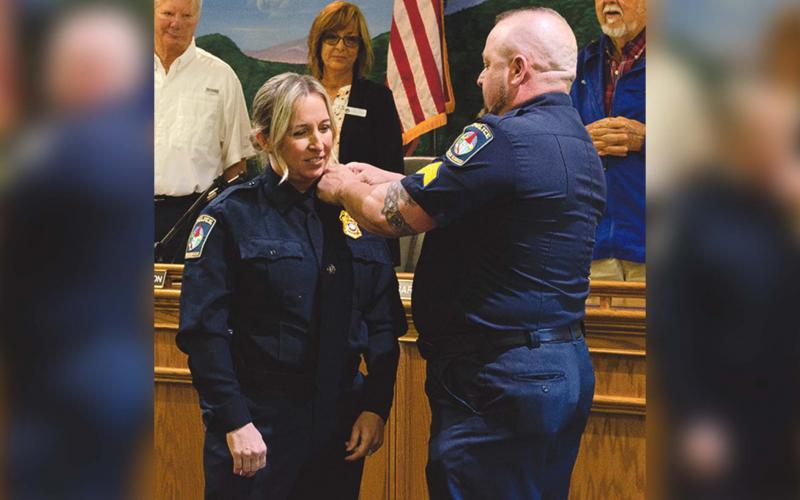 Husband Chris Barrett bestows pins upon his wife Aletha Barrett after she was sworn in as Chief of the Helen Police Department on May 10. (Ashley Blair/WCN)