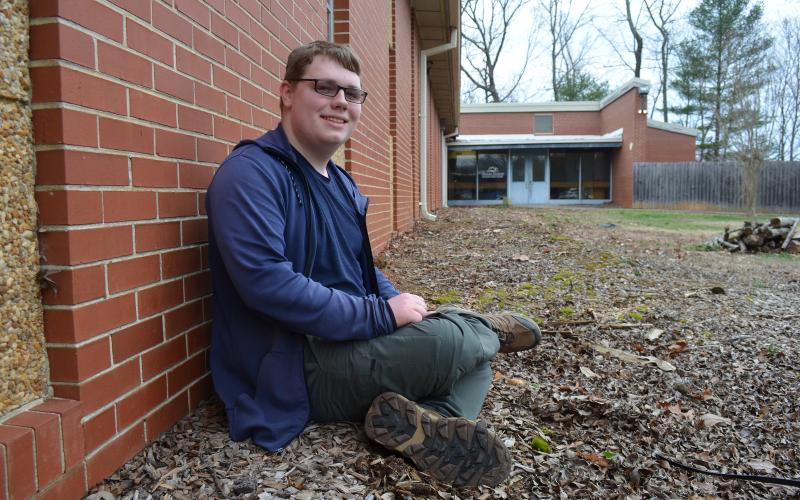 Seth Grindle, Mountain Education Charter School’s STAR Student, sits in the flower bed that he plans to clean up this spring for his Eagle Scout project. (Photo/Samantha Sinclair)
