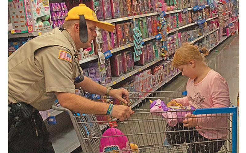 Faith Gill checks out a My Little Pony toy as Deputy and School Resource Officer Josh Smith gives her a ride in the cart. (Photo/Noah Johnson)