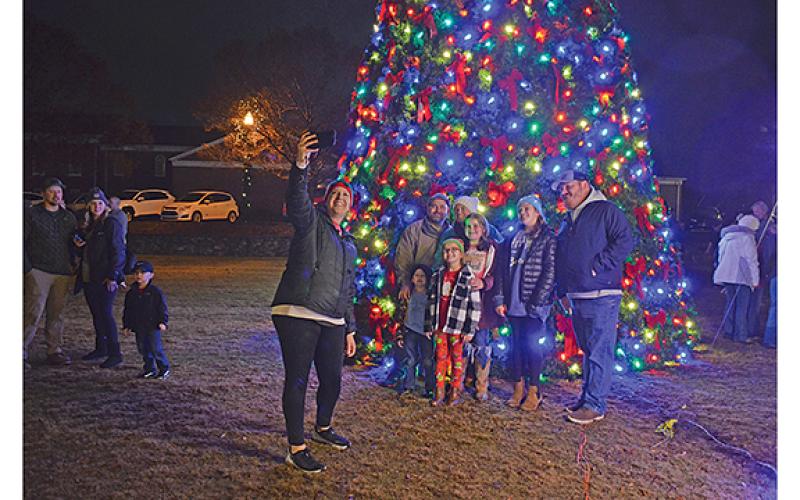 Lori Pressley takes a photo of herself and her family, the Schmidt Pressley family, after the tree is lit in Freedom Park. (Photo/Samantha Sinclair)