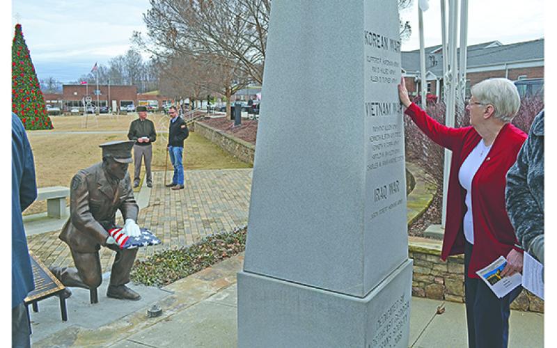 Terri Crumley brushes her hand over the side of the White County War Memorial where her brother’s name is etched as the new Families of the Fallen monument faces the memorial. (Photo/Samantha Sinclair)