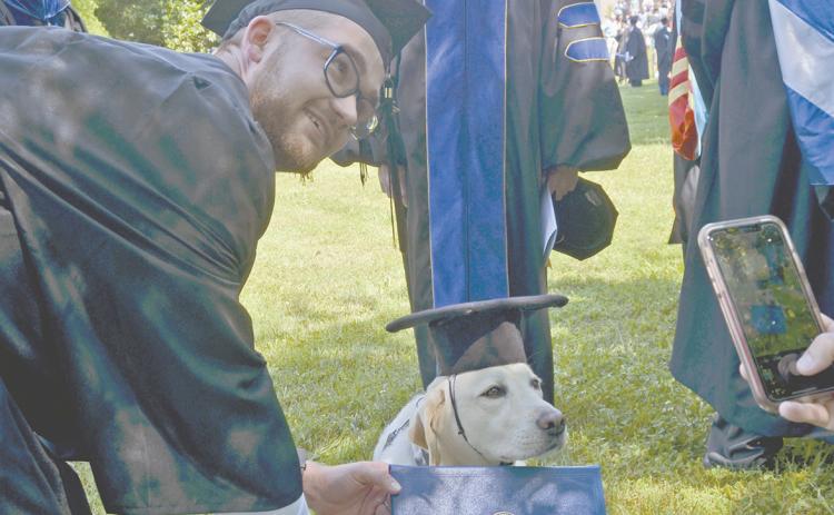 Aaron Abbs leans down to get a photo with his dog, Rachel, who accompanied him during graduation. (Photo/Wayne Hardy)