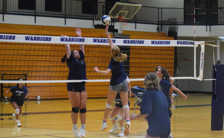 Claire Beckman, right, tips a ball at the net while Camryn Dorsey goes up for the block during practice Wednesday morning at the WCHS gym. (Photo/Mark Turner)