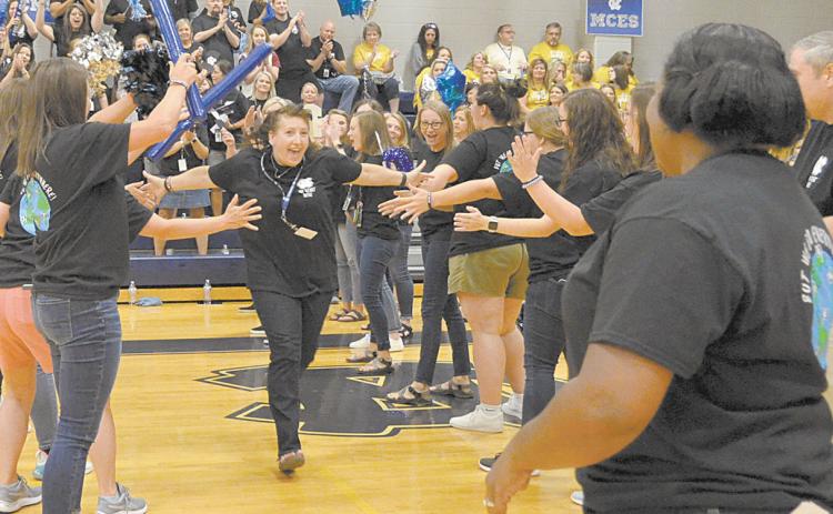 White County Middle School’s Dawn Powell runs through a lineup of fellow teachers on her way to celebrate with WCMS Principal Nara Allen during festivities a the school system’s back to school pep rally Aug. 2. (Photo/Wayne Hardy)