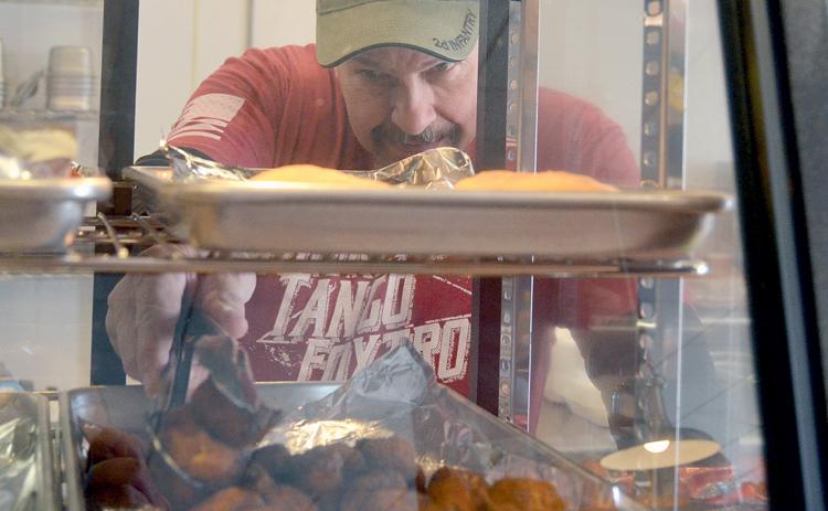 Cajun Specialties co-owner David Spikes grabs some Cajun bites from a deli shelf. (Photo/Wayne Hardy)