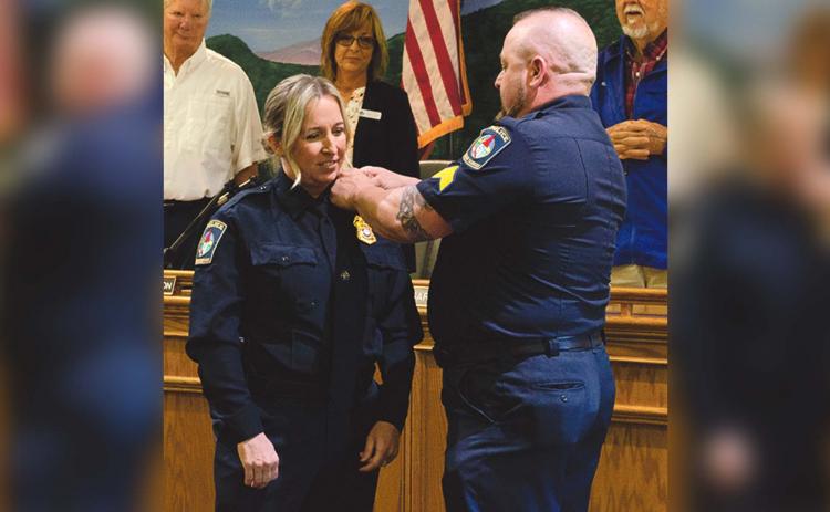 Husband Chris Barrett bestows pins upon his wife Aletha Barrett after she was sworn in as Chief of the Helen Police Department on May 10. (Ashley Blair/WCN)