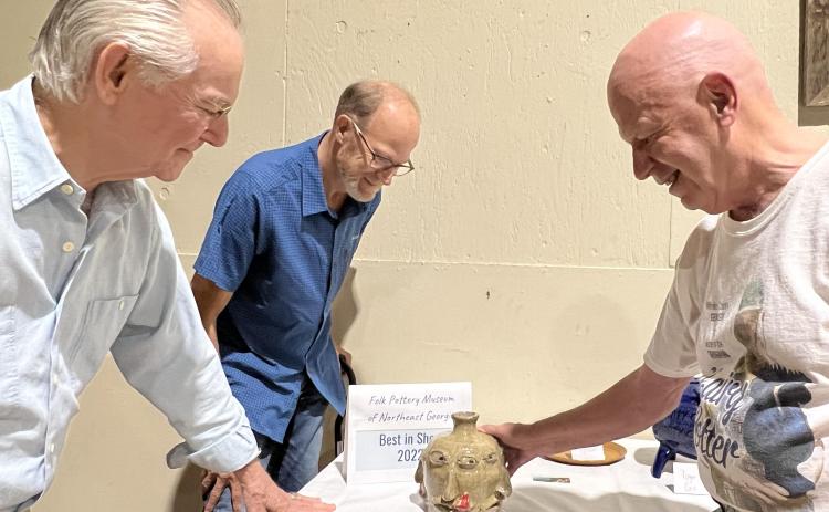 From left, Folk Pottery Museum trustees and judges John Luhn, Stewart Swanson and Bill House admire the “Best of Show” four-face jug created by Daniel Bollinger.