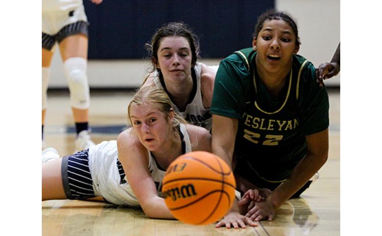 White County's Claire Beckman, left,  and Kylie Watkins, and Wesleyan's Desiree Davis scramble on the floor for a loose ball during the region opener last Friday night. (Photo/Staci Sulhoff)
