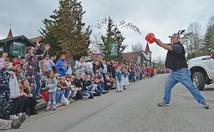 Matthew Akins of the American Red Cross tosses a bucketful of lollipops to the crowd gathered to watch Helen’s Annual Christmas Parade Saturday. (Photo/Samantha Sinclair)