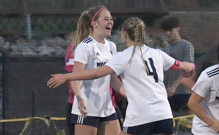 Callie Armour, left, celebrates with Anna Tatum after scoring an overtime goal that gave the Lady Warriors a 1-0 win over Hebron Christian last week in the opening round of the Class AAA state soccer tournament last week.  (Photo/Mark Turner)