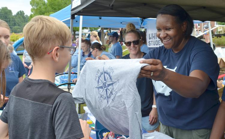 At Saturday’s Back to School Bash, White County Middle School Principal Nara Allen presents a t-shirt to student Gavin Gabhart as White County High School Principal Mary Anne Collier looks on. For more photos from the event, see Page 6A. (Photo/Samantha Sinclair)