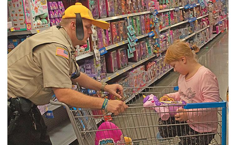 Faith Gill checks out a My Little Pony toy as Deputy and School Resource Officer Josh Smith gives her a ride in the cart. (Photo/Noah Johnson)