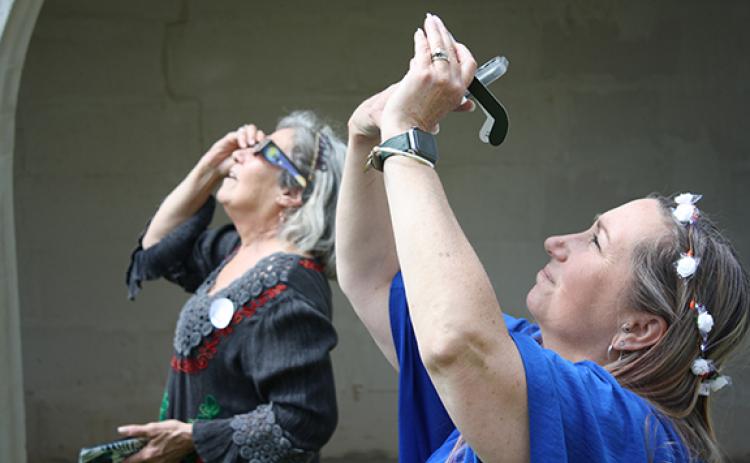 Mona Painter and Donna Highsmith watch the eclipse through their protective glasses. One popular method to try and get a good photo of the eclipse was to cover your phone camera with the protective glasses. (Photo/Eric Tiongson)
