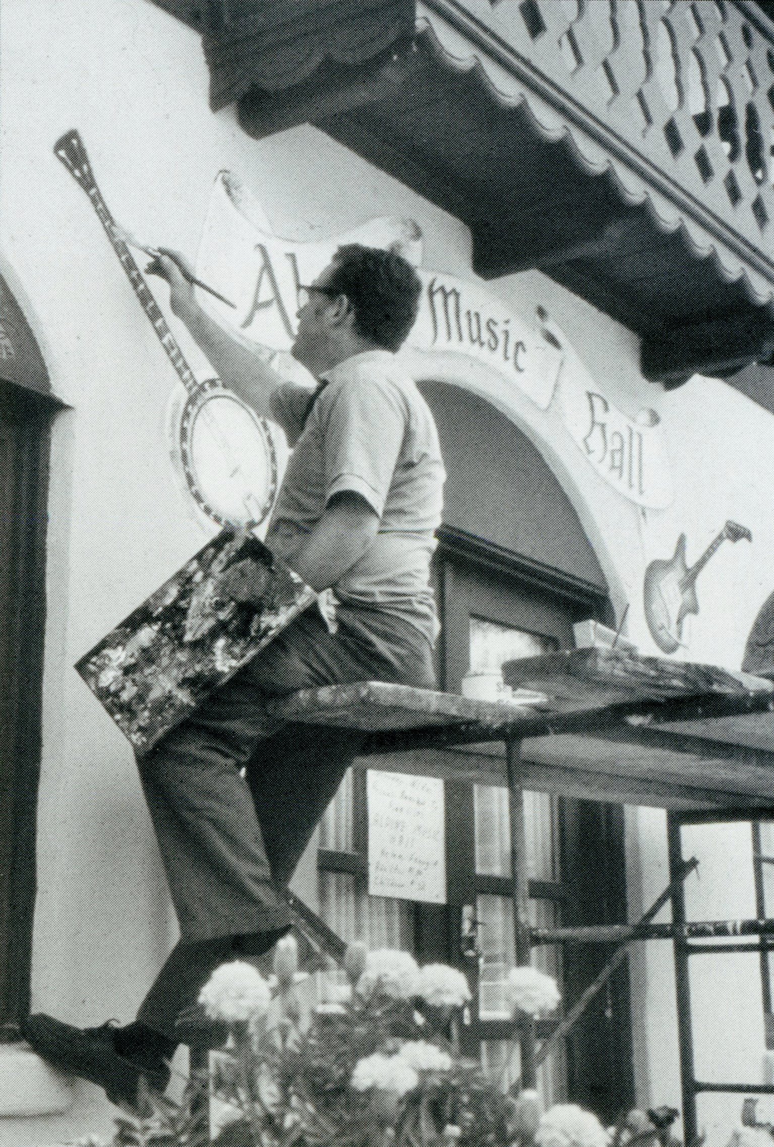 Artist John Kollock paints a mural on the side of an alpine-themed building. Photo courtesy of David Greear