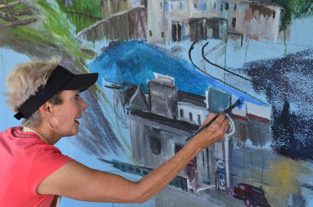 Anna Wilkins works on adding the river to the mural. (Photo/Stephanie Hill)
