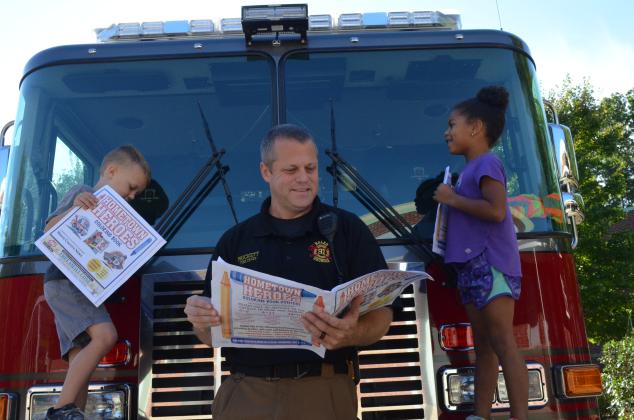 Beckham Vandegriff and Zurie Michele, kindergarteners at Mount Yonah Elementary School, were excited to look through the Hometown Heroes coloring book with Helen Fire Chief Jody Prickett. (Photo/Stephanie Hill)