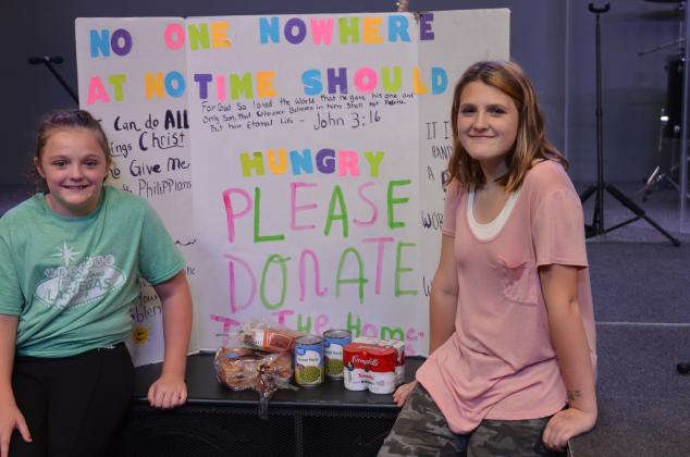 Mary and Grace are shown with a poster they made to promote their effort.