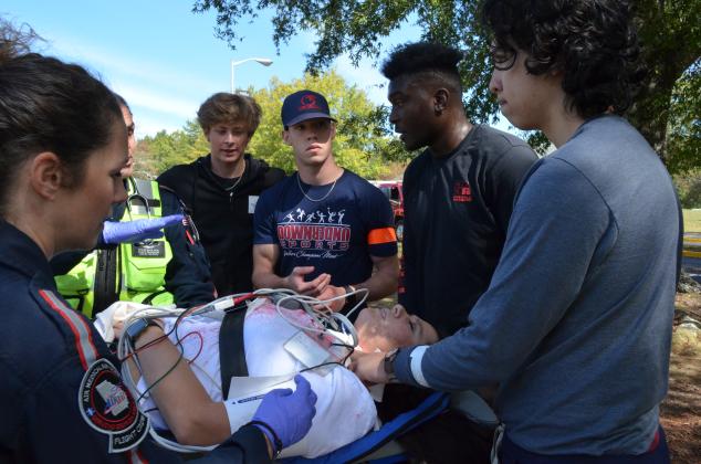 Cody Harris, Donnie Swinson, Khalil Belk and Josh Thereur listen to Steve Yook, flight paramedic, and Nyssa Hattaway, flight nurse, with AirLife Georgia about how to secure a patient before she are flown in the helicopter to a hospital. (Photo/Stephanie Hill)