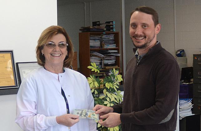 Elaine Jones, left, of Hartwell, receives $100 from Michael Hall, publisher and editor of The Hartwell Sun. Jones’ photo of a heron flying over Lake Hartwell at sunrise (shown at right) was selected as the winning photo to be used on the cover of Lake Living magazine’s winter 2019 edition. (Photo/LaDonna Harris, CNI News Service)