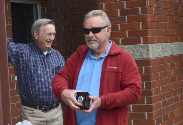 Melton, at right, shows the watch he received as a retirement gift, presented at the conclusion of the drive-by celebration.