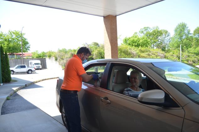 Terry Savoy places a meal in the car of Janelle and James Castleberry as part of the White County Senior Center’s drive-thru pick up service offered during the facility’s closure due to the COVID-19 pandemic. (Photo/Wayne Hardy)