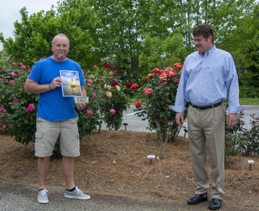 Spring Lake Living cover contest winner Douglas Whiddon of Cleveland holds his photo of a sailboat in the sunset on Lake Lanier after Regional Publisher Alan NeSmith presented him with his prize. (Photo/Kimberly Brown)