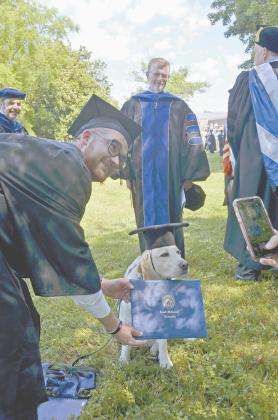 Aaron Abbs leans down to get a photo with his dog, Rachel, who accompanied him during graduation. (Photo/Wayne Hardy)