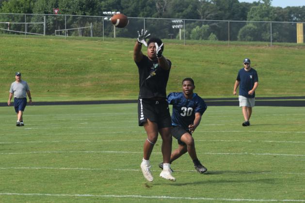 Running back Zion McMullen hauls in a pass in front of linebacker Xzavier Whitlock during a 7-on-7 session last week. (Photo/Mark Turner)