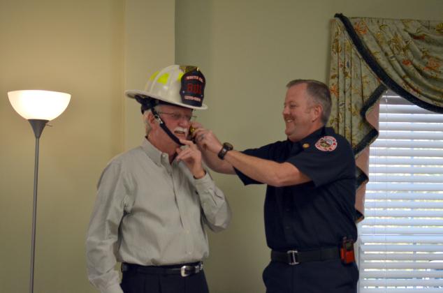 White County Fire Chief Seth Weaver assists Sheriff Neal Walden with securing a fire helmet presented as a gift.