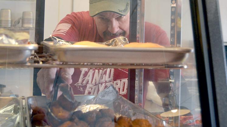 Cajun Specialties co-owner David Spikes grabs some Cajun bites from a deli shelf. (Photo/Wayne Hardy)