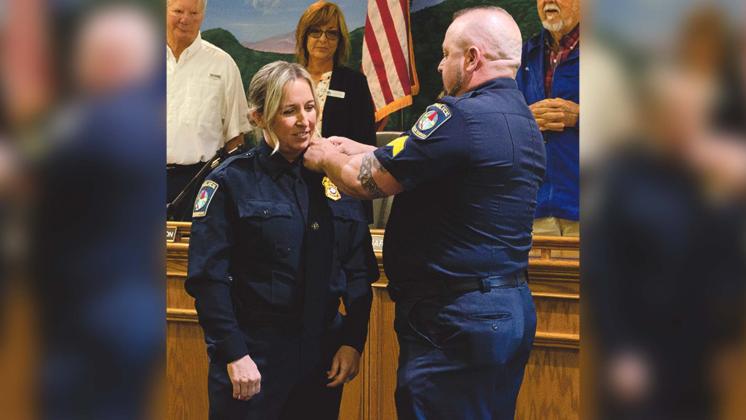 Husband Chris Barrett bestows pins upon his wife Aletha Barrett after she was sworn in as Chief of the Helen Police Department on May 10. (Ashley Blair/WCN)