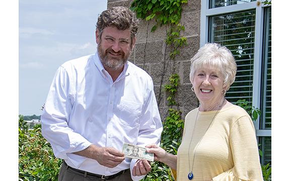 Cornelia resident Donna Shirley receives her $100 prize money from Alan NeSmith, Community Newspapers Inc. chairman. Shirley’s photograph of the double waterfalls that make up Anna Ruby Falls graces the cover of the 2023 summer edition of The Mountain Traveler magazine. (Photo/Kimberly Brown)