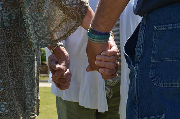 Gloria Hughes, Kim Fletter and Hal Miller join hands as they pray for each other during National Day of Prayer at Freedom Park. (Photo/Samantha Sinclair)