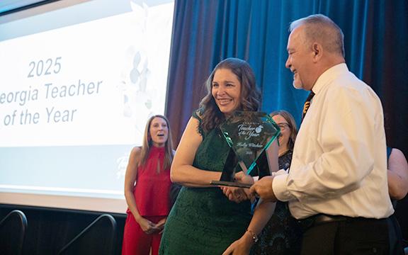 Tesnatee Gap Elementary Teacher Holly Witcher accepts the 2025 Georgia Teacher of the Year award from State Superintendent Richard Woods as other finalists celebrate.  (Photo/Georgia Department of Education)