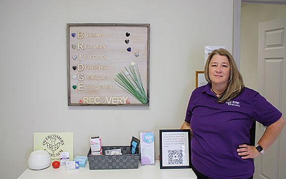 Shelley Sidders poses with a framed piece of art that spells out the B.R.I.D.G.E acronym in Bridge Recovery. (Photo/Eric Tiongson)