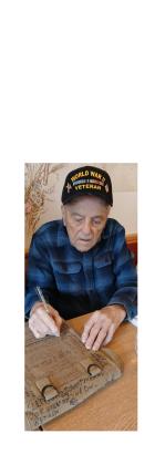 Andy Negra, 101, signs a World War II-era map bag. The map bag was mailed in for signatures and has been autographed by more than 100 World War II veterans. Negra served in the U.S. Army beginning in 1943 and fought in the Battle of the Bulge. SUBMITTED PHOTO