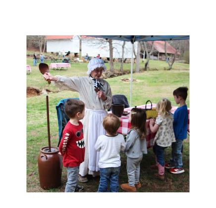 Reenactor Peggy Berry demonstrates dairy farming practices for children during the Cows Come Home Celebration at Hardman Farm State Historic Site. CARLY HENDERSON/WCN