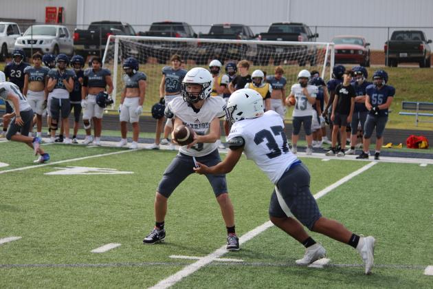 Ashton Elrod, right, hands the ball off to Kiyan Dorsey during a junior varsity team period at Monday's practice session.