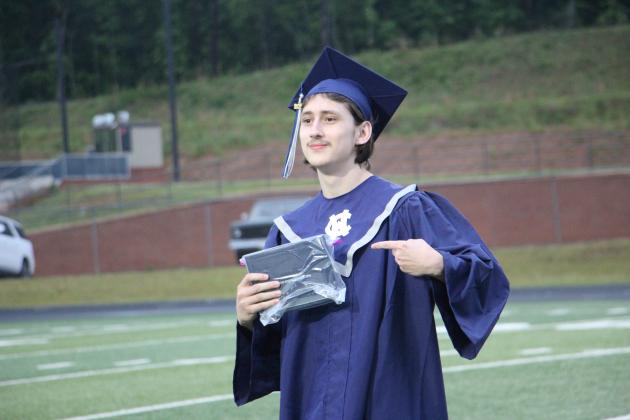 A graduate proudly points to his diploma during the 2026 White County High School graduation ceremony. CARLY HENDERSON/WCN